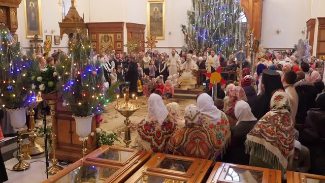a Wise and Bearded Orthodox Church Archbishop Tells People About Jesus Christ and Sits Near a Huge Christmas Pine Tree, Installed in a Cathedral