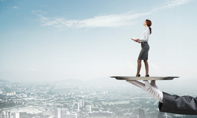 Attractive businesswoman on metal tray with red book in hands against cityscape background