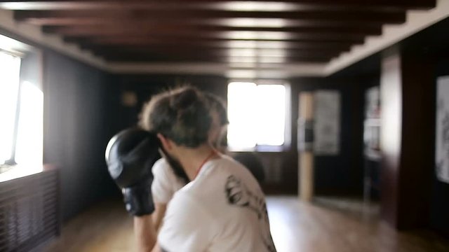 The twin brothers in boxing gloves sparring in the training hall. Chinese martial arts.
