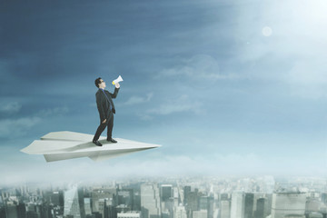Businessman with megaphone on paper plane