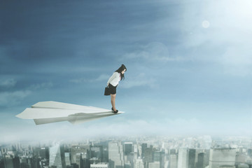 Fototapeta na wymiar Businesswoman flying with a paper aeroplane