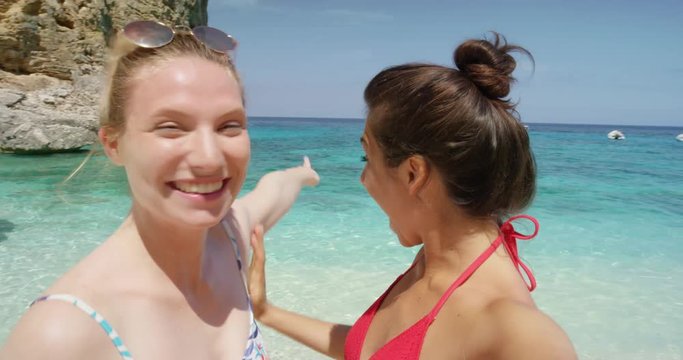 Best friends having video chat using smart phone on beach taking selfie photograph smiling blowing kiss waving enjoying tropical nature background view on  summer vacation travel adventure POV