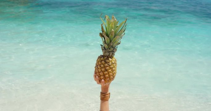 Close up hand holding pineapple with clear blue water background on tropical beach summer vacation holiday fresh fruit healthy lifestyle concept