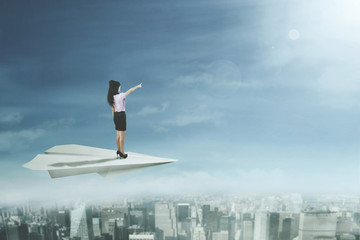 Female entrepreneur stands on paper plane