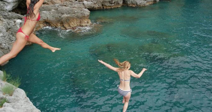 Athletic women jumping from cliff into sea best friends enjoying European summer holiday travel vacation adventure in Amalfi Coast Italy - Powered by Adobe
