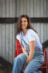 Farm girl siiting on a chair and smiling for a camera