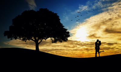 Loved ones silhouettes and single tree at sunset