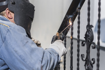 A worker welding metal handrails on the stairs. Ukraine.