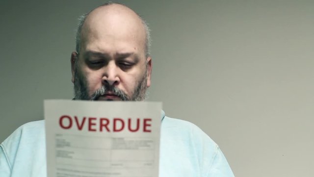 Depressed man looking at overdue bill