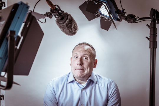 Scared and nervous business man under video lights and microphone about to be interviewed on camera.