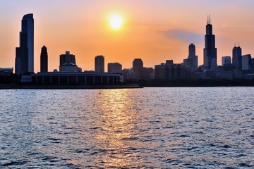 Obraz premium The setting sun creates a colorful glow in the sky and into Chicago's Monroe Street Harbor as it dips toward the horizon. 