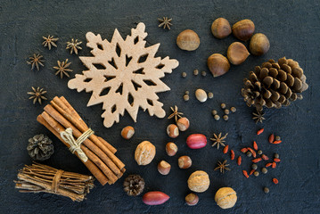 Obraz na płótnie Canvas Christmas season flat lay or overhead view of nuts, a gingerbread snowflake, pine cones and spices