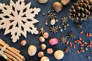 Christmas season flat lay or overhead view of nuts, a gingerbread snowflake, pine cones and spices