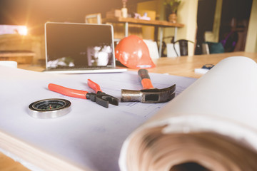 helmet, compass, hammer, blueprint, laptop and other construction  tools on wooden table