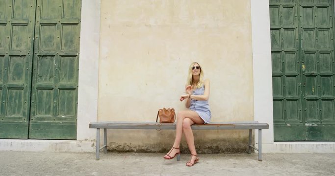 Tourist woman using smartwatch looking for restaurant reviews online exploring small italian town relaxing sitting on bench enjoying European summer holiday travel vacation adventure 
