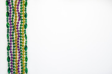 A border of Mardi Gras beads in traditional festive Mardi Gras colors on a white background in horizontal or landscape format with lots of copy space