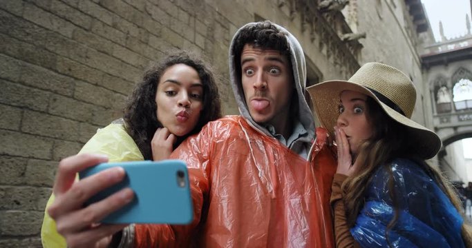 Best friends taking selfie using smartphone in Barcelona on Vacation in rainy weather enjoying European summer holiday travel adventure