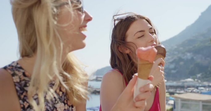 Young women eating ice cream on beach Best friends licking Italian Gelato outdoors in summer sunshine Girls enjoying European vacation travel adventure Amalfi Coast  Italy