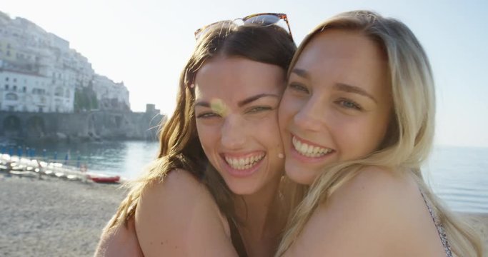 Best friends hugging each other giving kiss on cheek Tourist woman enjoying sunset on beach girlfriend travellers enjoy European travel adventure summer vacation Amalfi Coast Italy