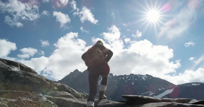 Portrait of Woman Climber at top of mountain in nature with blonde hair blowing in wind above the clouds view Hiker Girl trekking in Norway Slow Motion