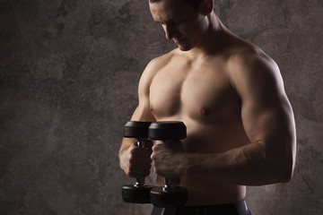 Young strong male athlete demonstrating his torso, athlete with dumbbells