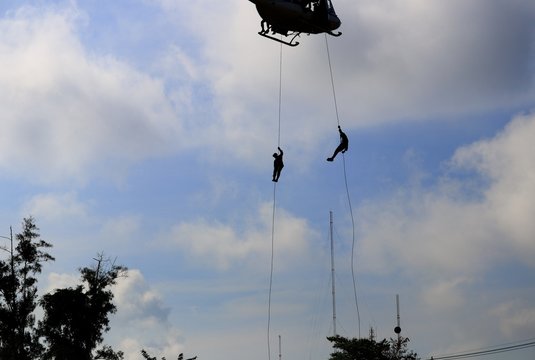silhouette Soldier rappelling from helicopter in blue sky