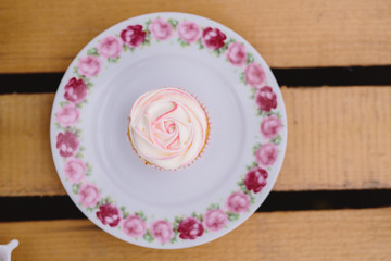 Cupcake auf rosa Teller mit Blumen und Holzbrett