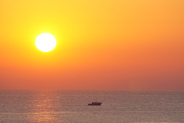 Fischerboot vor aufgehender Sonne