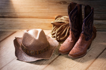 Cowboy women's boots, hat, rope on a wooden background