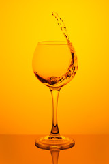 Splash of water in a glass on yellow