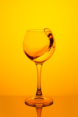 Splash of water in a glass on yellow