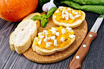 Bruschetta with pumpkin and feta on dark board