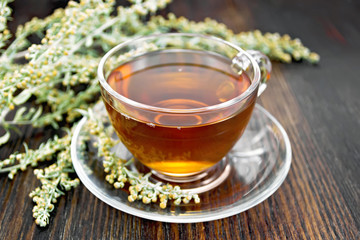 Tea with gray wormwood in glass cup on table