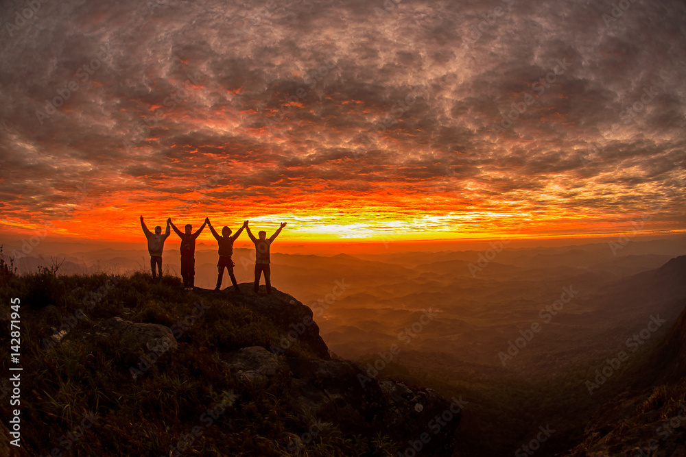 Wall mural silhouette of the success team on the peak of mountain. sport and active life