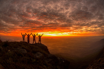 Silhouette of the success team on the peak of mountain. Sport and active life