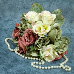 Bouquet of silk roses with a string of pearls on an elegant background