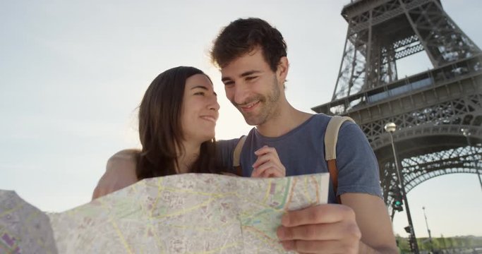 Tourist couple reading City Map under Eiffel Tower Paris planning European holiday Summer Vacation