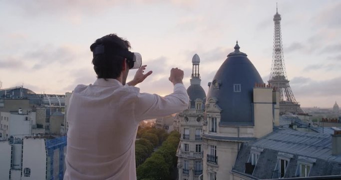 Tourist Man wearing virtual reality headset looking at Eiffel Tower Paris from hotel balcony watching 360 video imagination concept at sunrise sunset