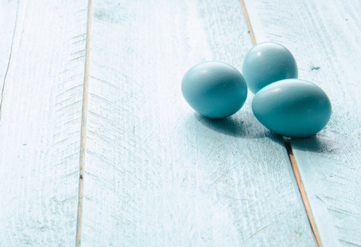 High key minimalist image of three robin's eggs on a rustic aqua board  surface