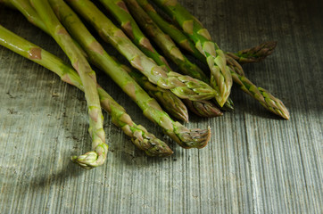 Asparagus spears on a textured slate surface with dramatic lighting