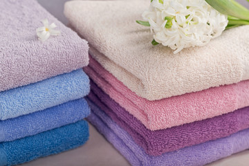 Two stacks of colorful bath towels with hyacinth flower on light background.