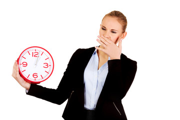 Yawning business woman holding office clock