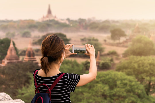 Female traveler photographing ancient pagoda at Bagan