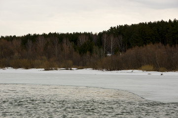 Edge of ice on the river bank. View of the shore from the boat.