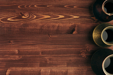 Hot coffee in different kind shabby turkish pots cezve with copy space on brown old wooden board background, top view. Rustic style.