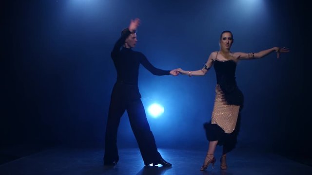 Salsa dancing pair of professional elegant dancers in smoky studio