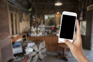 Hand holding smartphone with abstract blur old coffee shop for background