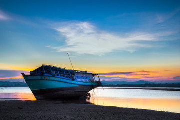 Naklejka premium Landscape of beautiful dramatic sunset sky in summer. Fishing boat on tropical beach in beautiful twilight time, Thailand.