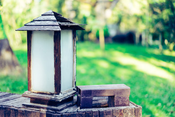 Lamp made of wood in the park with green trees.