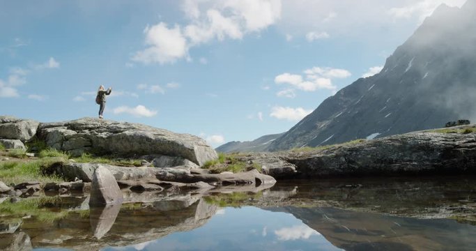 Woman taking photo at top of mountain Hiker girl above the clouds using smartphone photographing scenic landscape nature background view enjoying vacation travel adventure Romsdalen Valley Norway